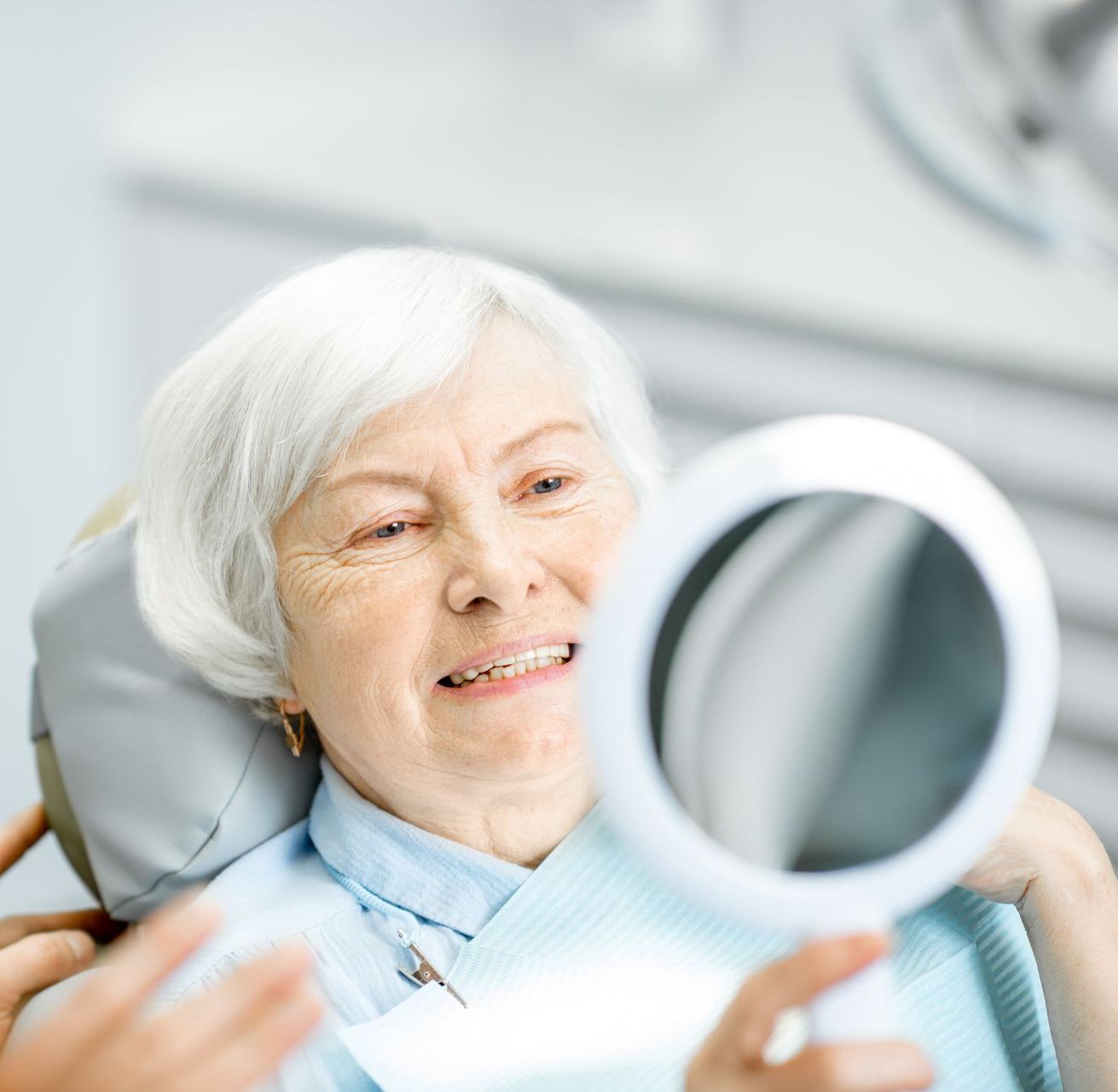 Fix a broken tooth with restorative dental care in Somerset NJ | Woman smiling in mirror | dentures and more