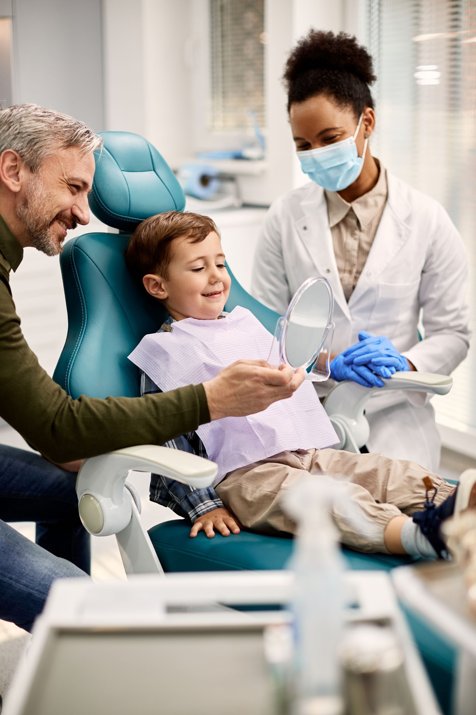 Kid smiling in mirror in dentist chair | Dentist for kids in Somerset, NJ