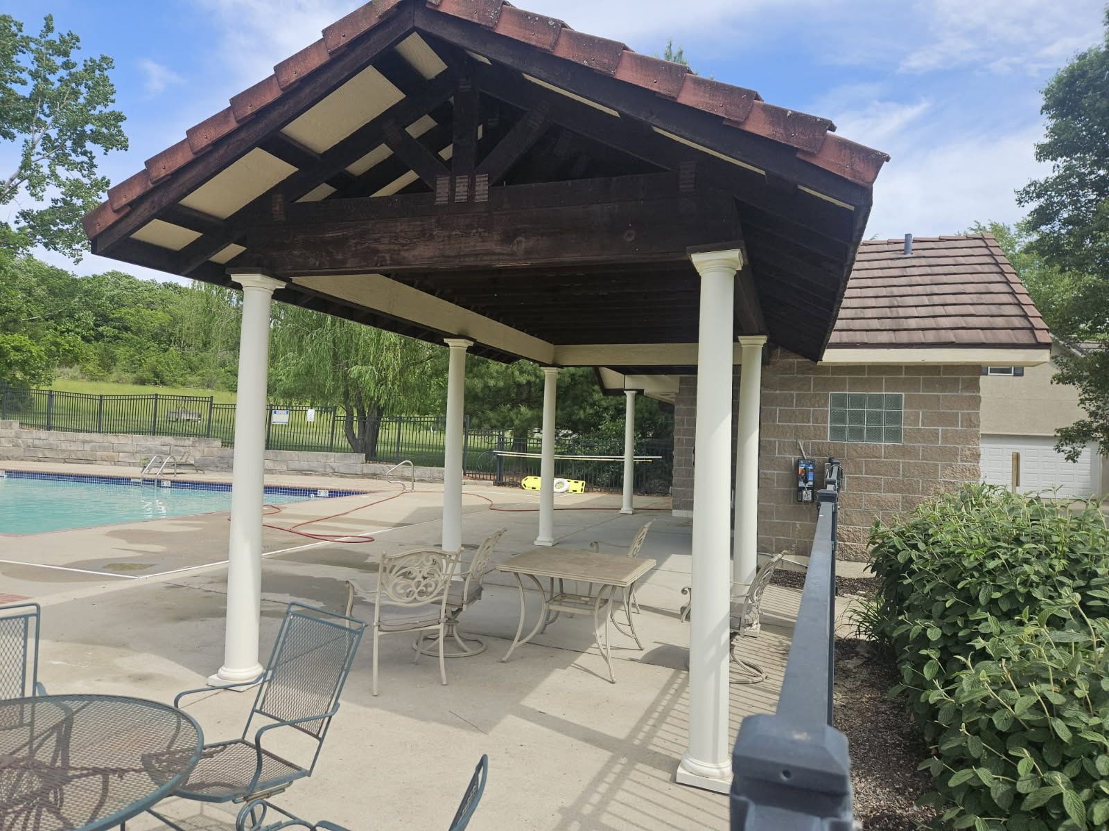 A gazebo overlooking a swimming pool with tables and chairs