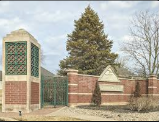Trees and bushes surround a sign for Saddle Ridge.