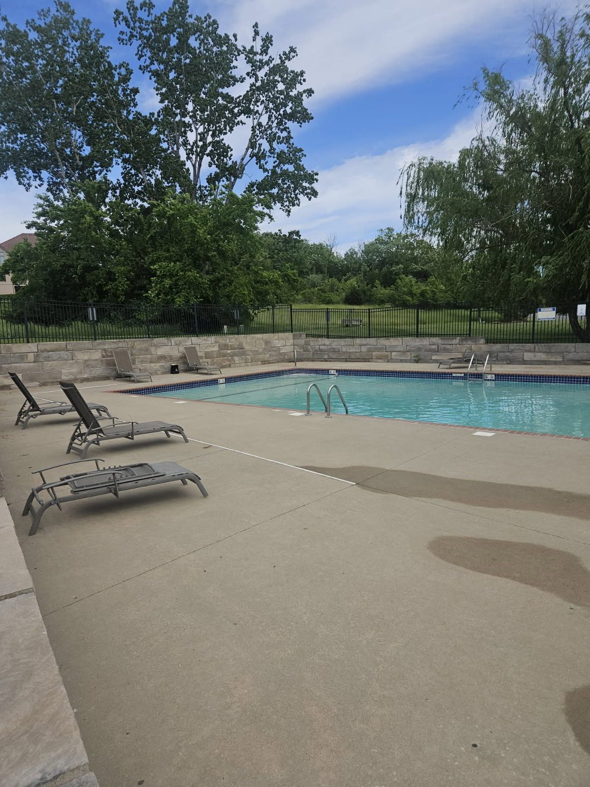 A large swimming pool surrounded by lawn chairs on a sunny day