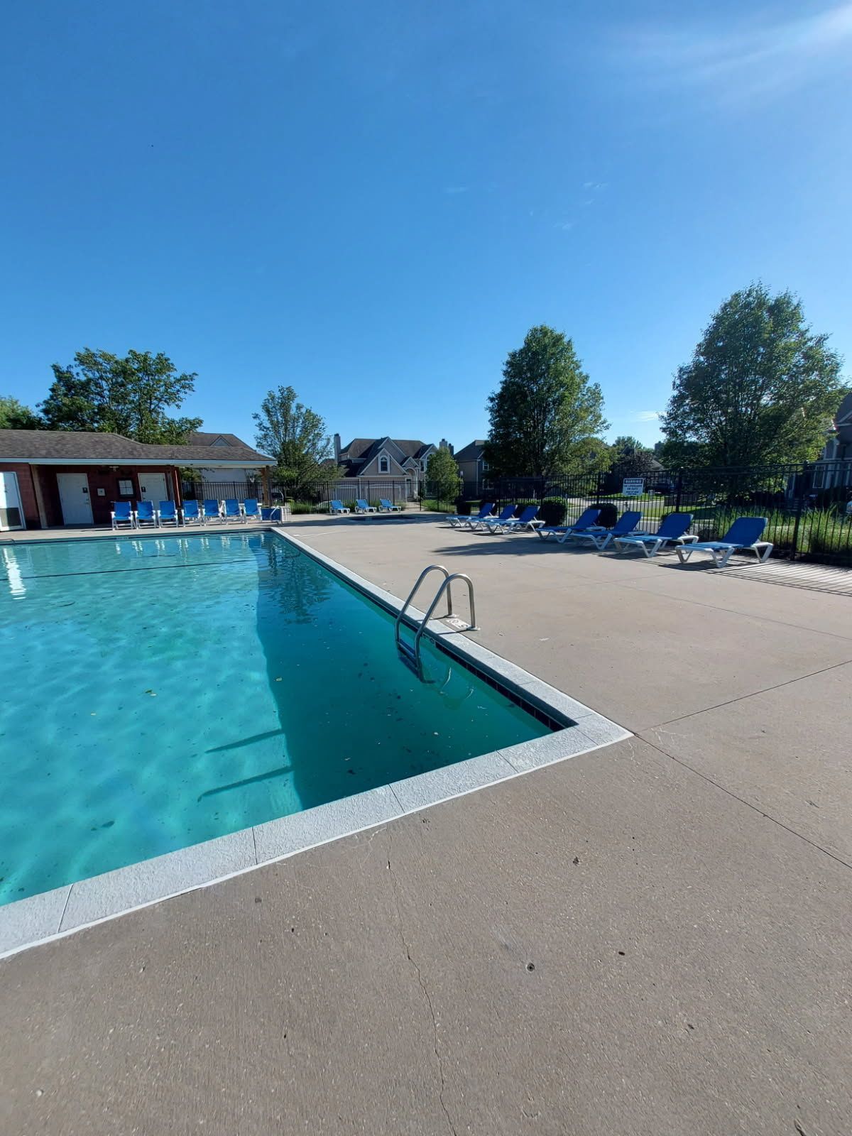A large swimming pool surrounded by chairs on a sunny day