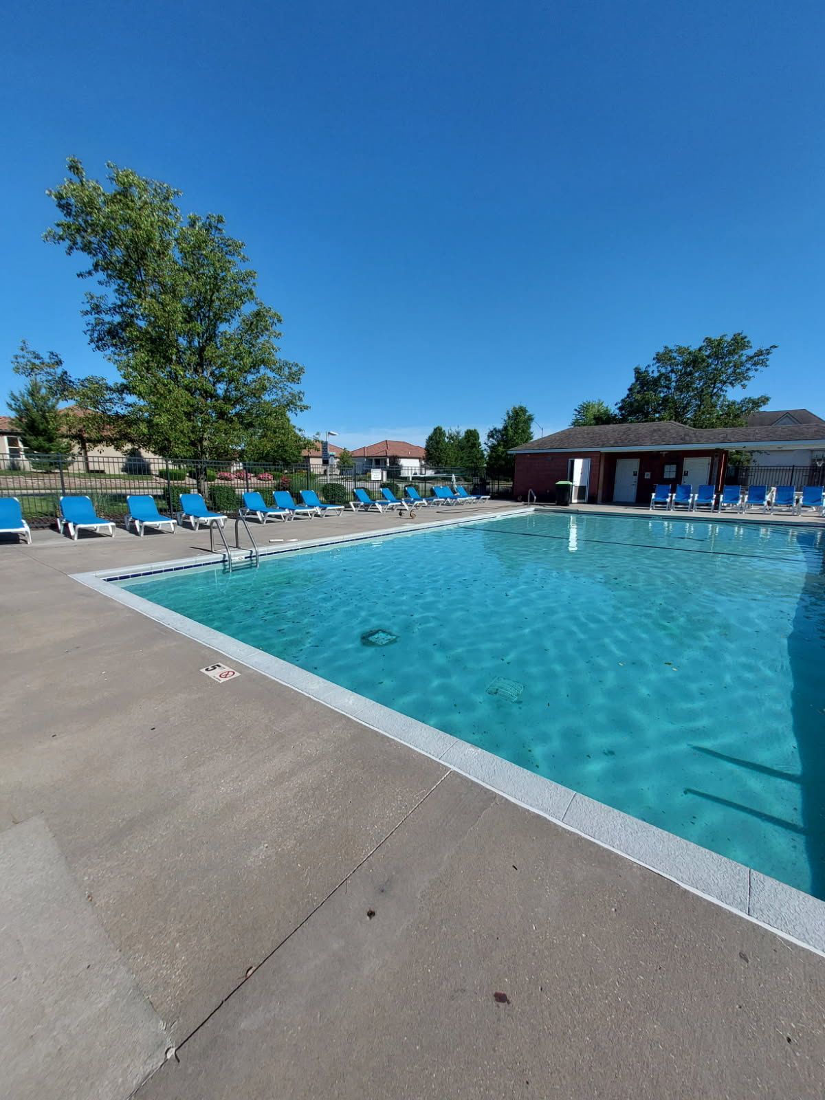A large swimming pool surrounded by chairs on a sunny day