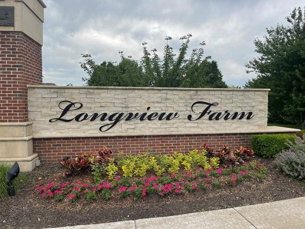 A sign for longview farm is surrounded by flowers