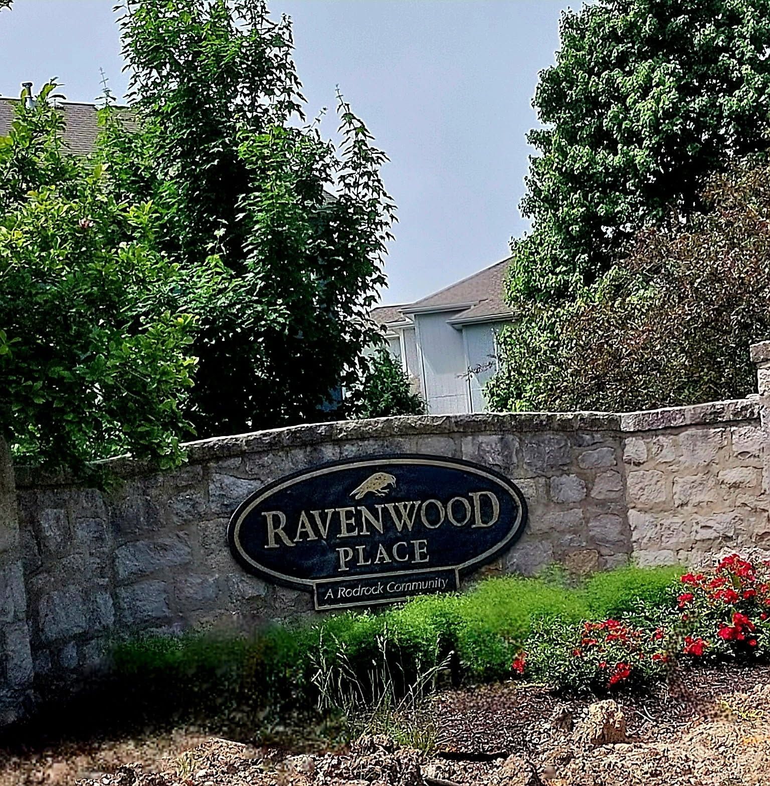 A stone wall with a sign that says ravenwood place