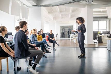 Woman presenting to group seated in a modern office.