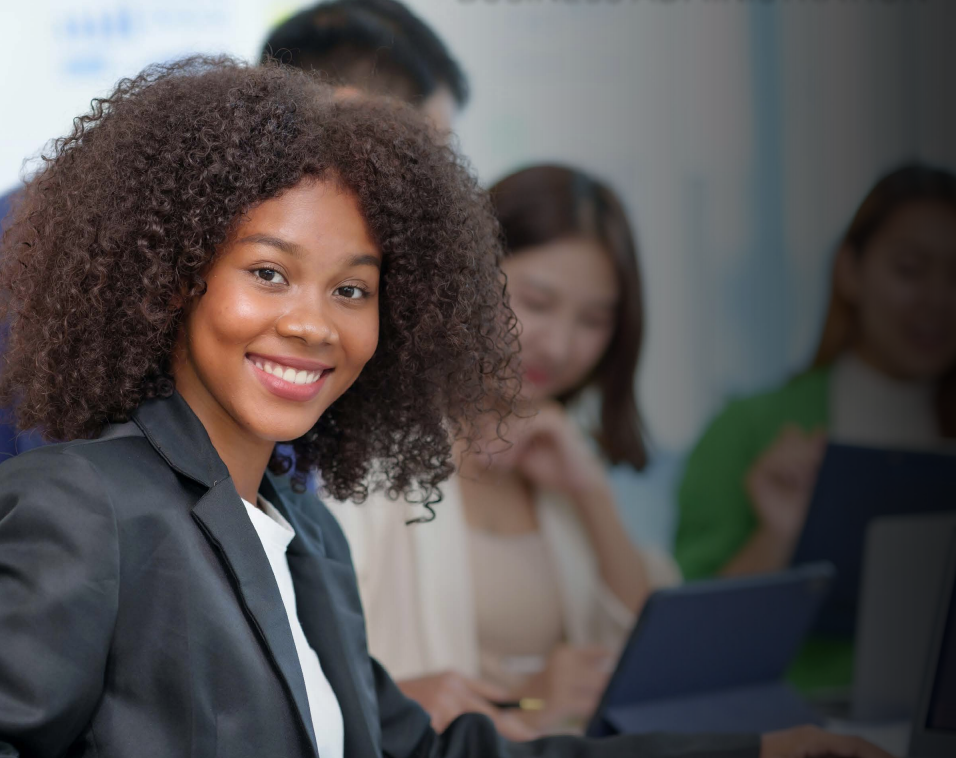 Woman with arms crossed, wearing blue polka dot shirt, standing outside a building, looking directly at the camera.