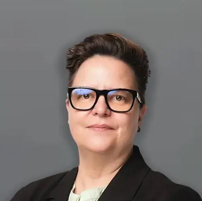 Woman with short dark hair, glasses, and a black blazer smiles at the camera. Dr Linda Meyer