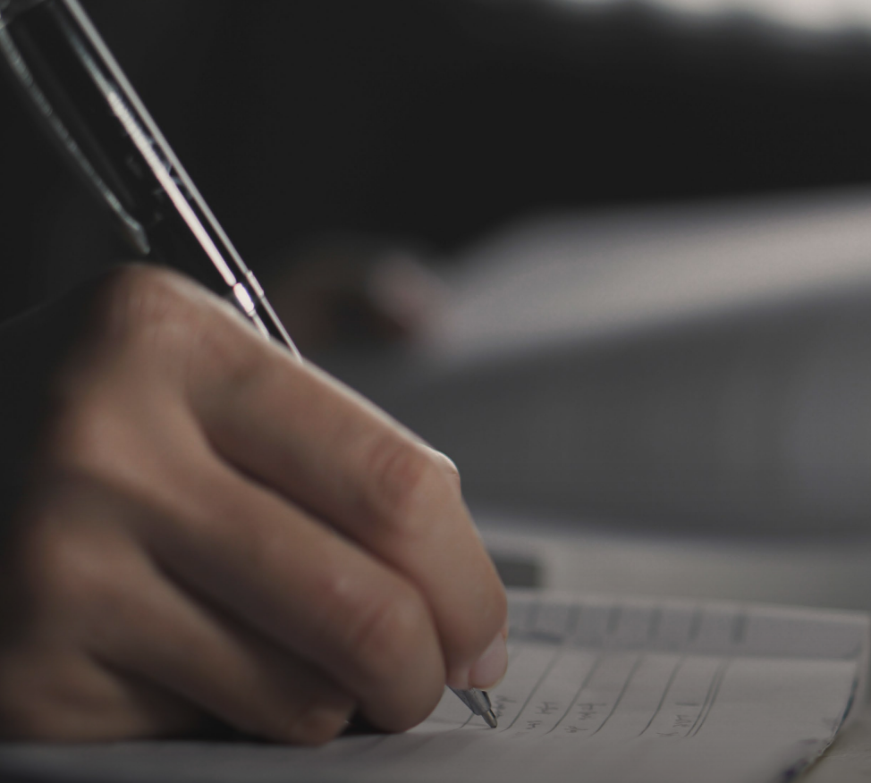 Woman with arms crossed, wearing blue polka dot shirt, standing outside a building, looking directly at the camera.