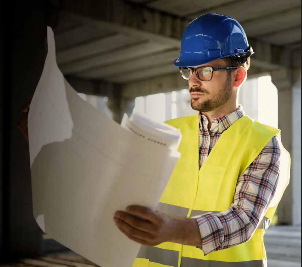 Woman with arms crossed, wearing blue polka dot shirt, standing outside a building, looking directly at the camera.