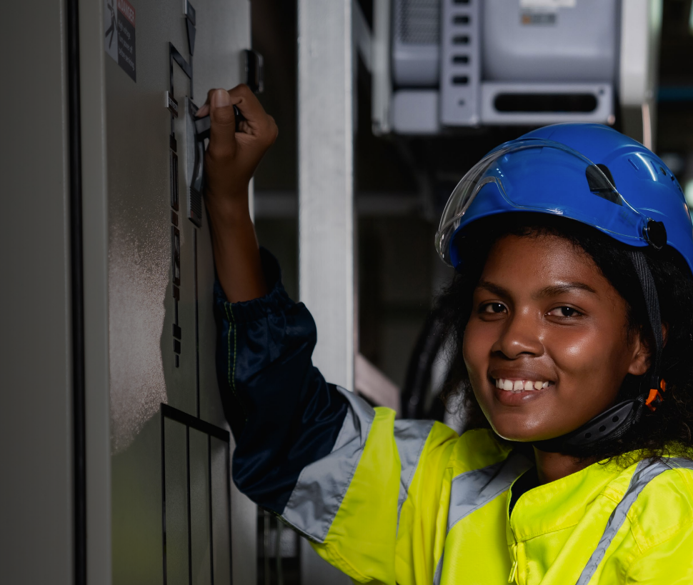 Woman in business suit with arms crossed, smiling, with colleagues in the background.
