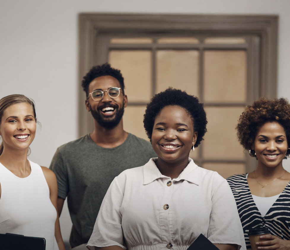 Woman with arms crossed, wearing blue polka dot shirt, standing outside a building, looking directly at the camera.