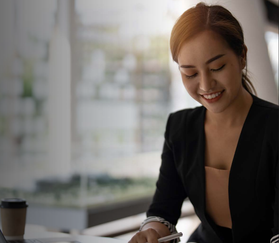 Woman with arms crossed, wearing blue polka dot shirt, standing outside a building, looking directly at the camera.