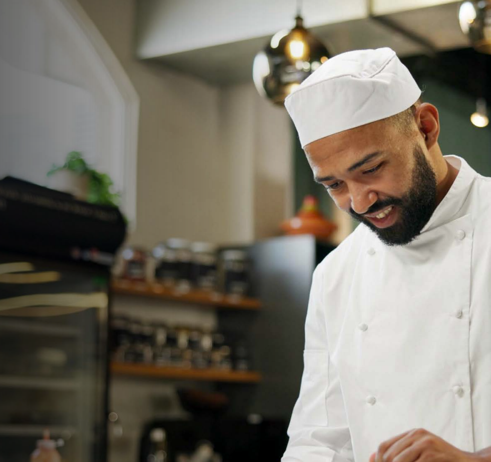 Woman with arms crossed, wearing blue polka dot shirt, standing outside a building, looking directly at the camera.