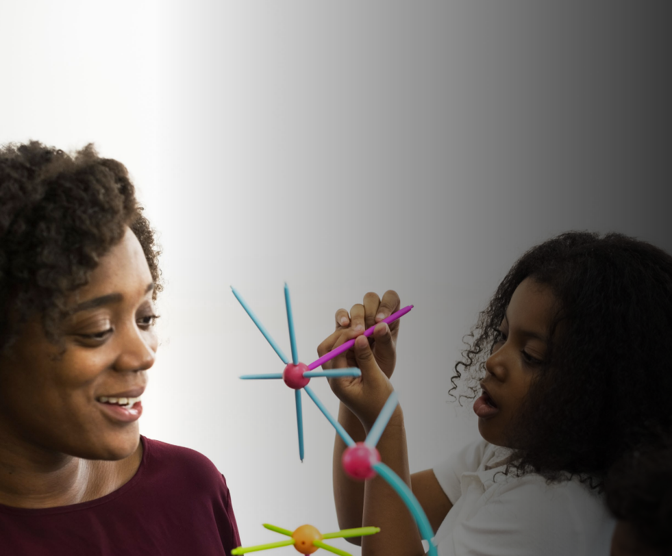 Woman with arms crossed, wearing blue polka dot shirt, standing outside a building, looking directly at the camera.