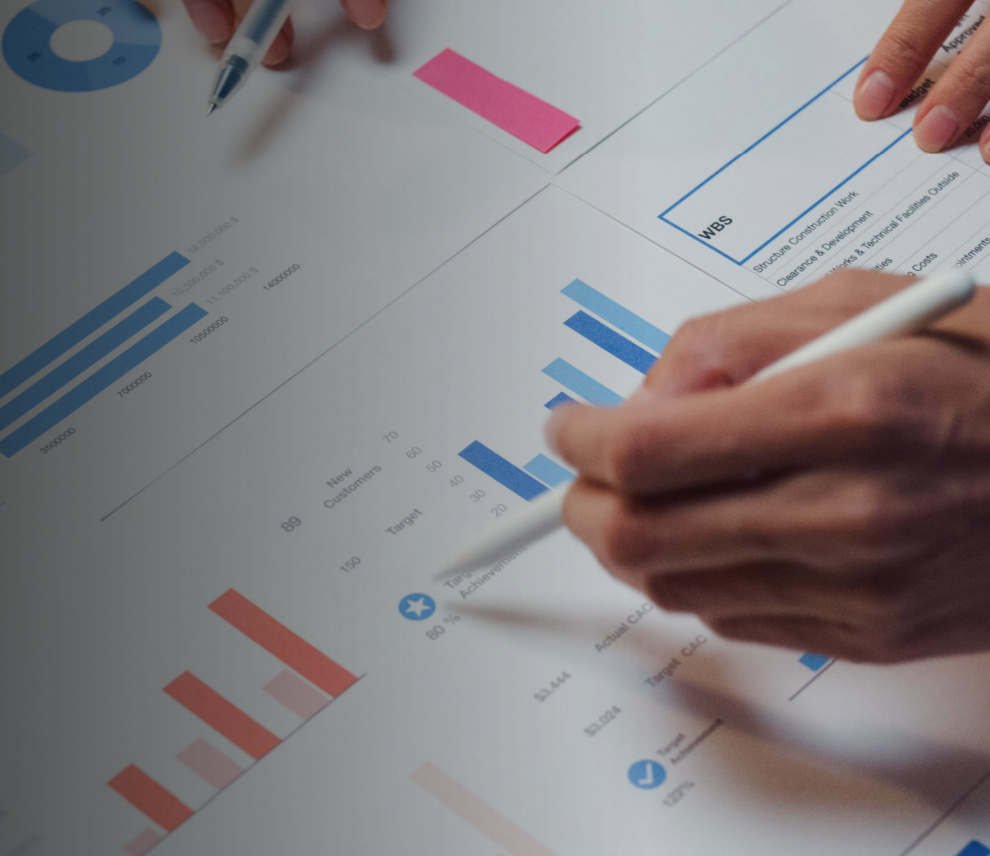 Woman with arms crossed, wearing blue polka dot shirt, standing outside a building, looking directly at the camera.