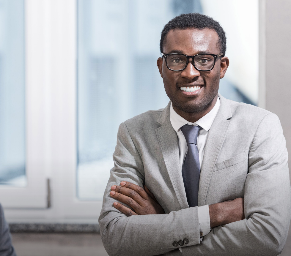 Woman with arms crossed, wearing blue polka dot shirt, standing outside a building, looking directly at the camera.