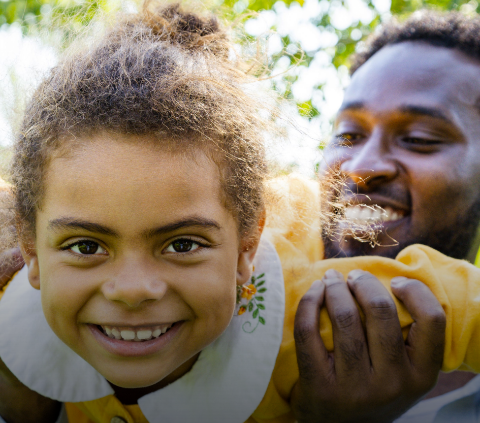 Woman with arms crossed, wearing blue polka dot shirt, standing outside a building, looking directly at the camera.