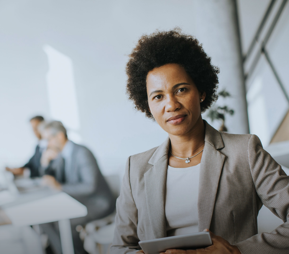 Woman with arms crossed, wearing blue polka dot shirt, standing outside a building, looking directly at the camera.