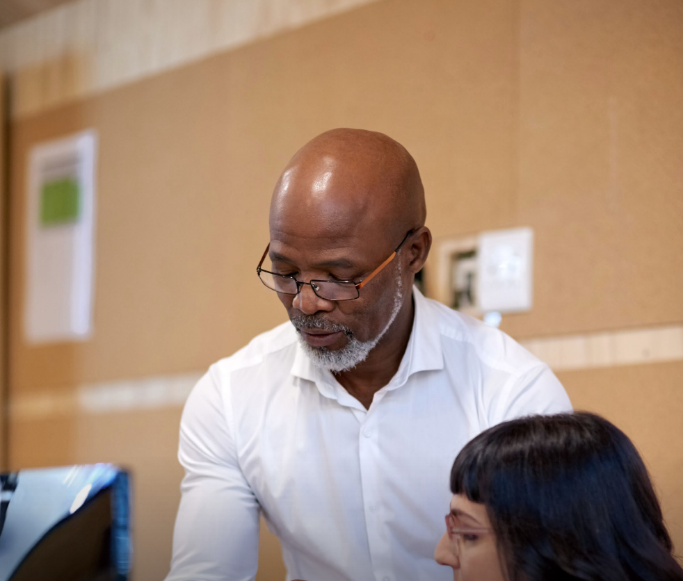 Woman with arms crossed, wearing blue polka dot shirt, standing outside a building, looking directly at the camera.