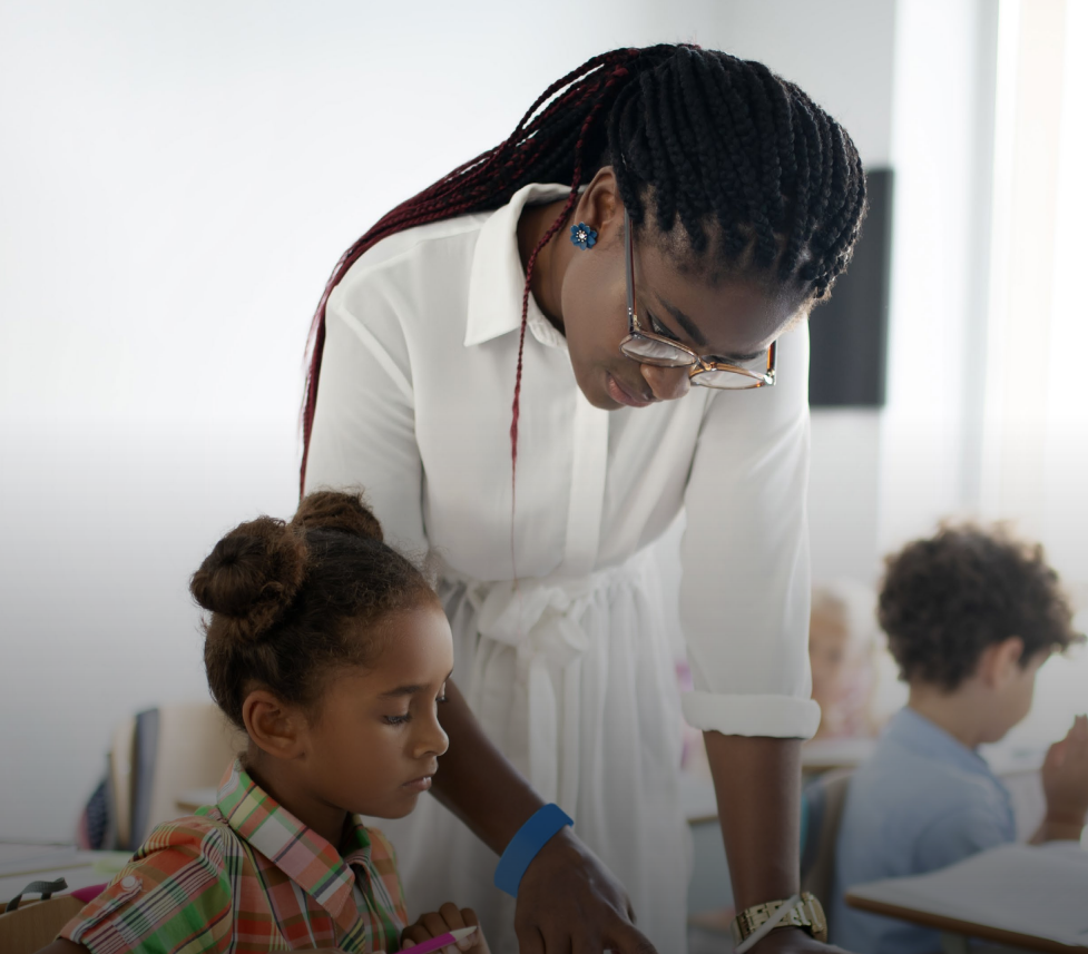 Woman in business suit with arms crossed, smiling, with colleagues in the background.