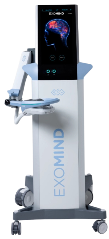 A woman stands beside an Exomind medical imaging device featuring a touchscreen display of a brain model.