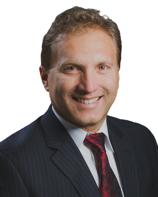 Headshot of a smiling person wearing a dark blue pinstriped suit, white collared shirt, and a dark red patterned tie.
