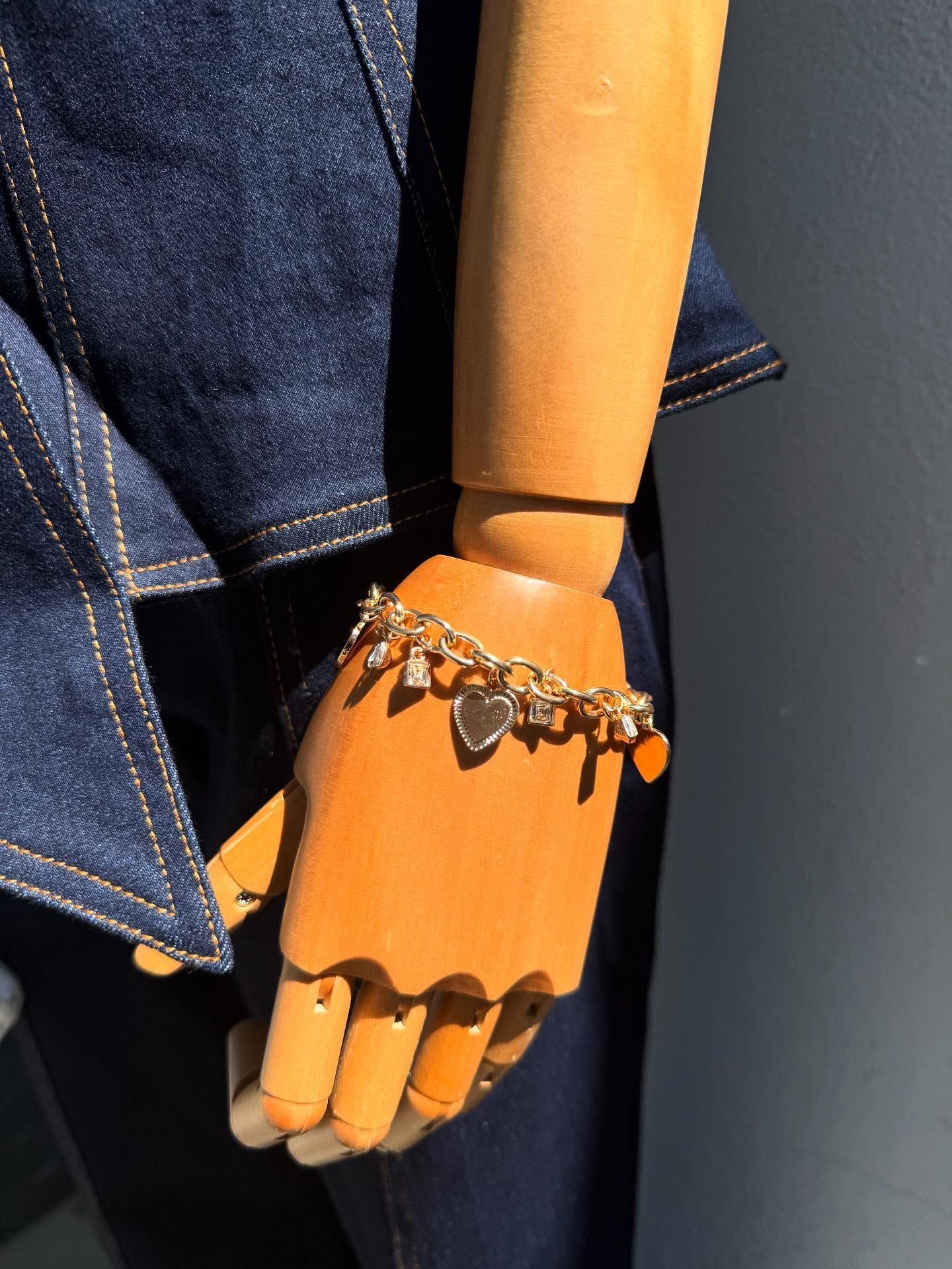 Mannequin hand with orange nails wearing a silver bracelet and denim jacket sleeve