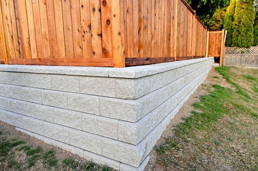 retaining wall corner Concrete Blocks With Wooden Fence In New Construction Garden Landscape Design — Fencer in South West Rocks, NSW