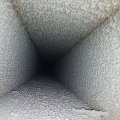 A person is holding a pair of gauges in front of an air conditioner.