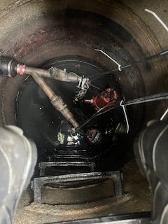 A manhole cover with a hose coming out of it.