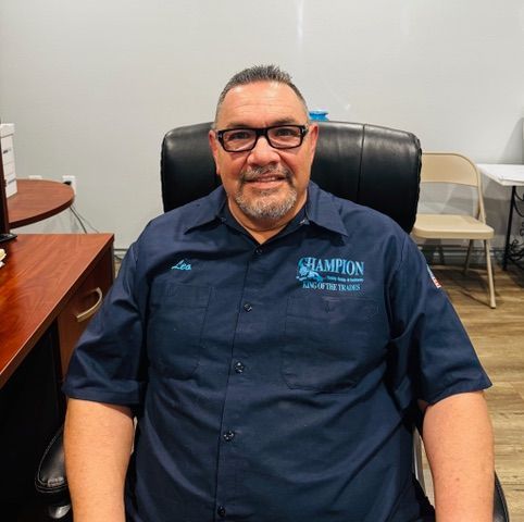 A man wearing glasses and a blue shirt is sitting in a chair.