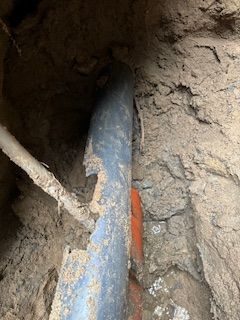 A pipe is laying in the dirt in a hole.