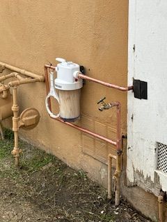 A water filter is attached to the side of a building.