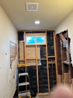 A bathroom under construction with a ladder and a window.