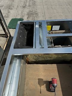 A person is working on a metal structure with a drill.