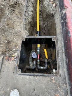 A yellow pipe is coming out of a manhole cover.
