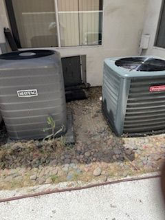 Two air conditioners are sitting next to each other on the side of a building.