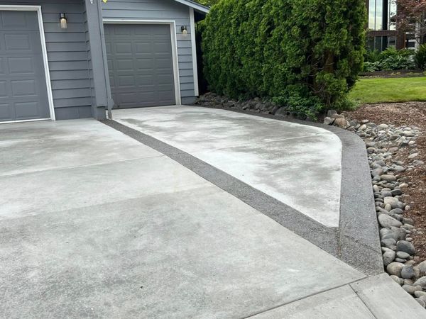Concrete driveway with a gravel drainage channel next to a garage.