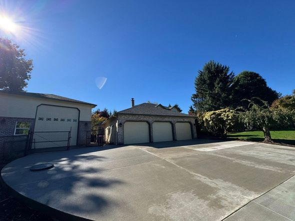 A three-car garage and a one-car garage with concrete driveway, under a bright blue sky.