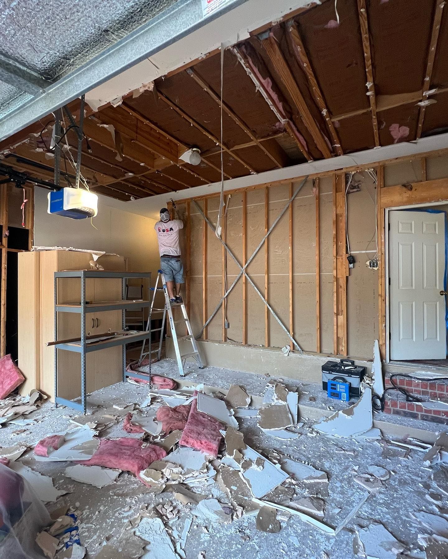 A man is standing on a ladder in a room that is being remodeled.