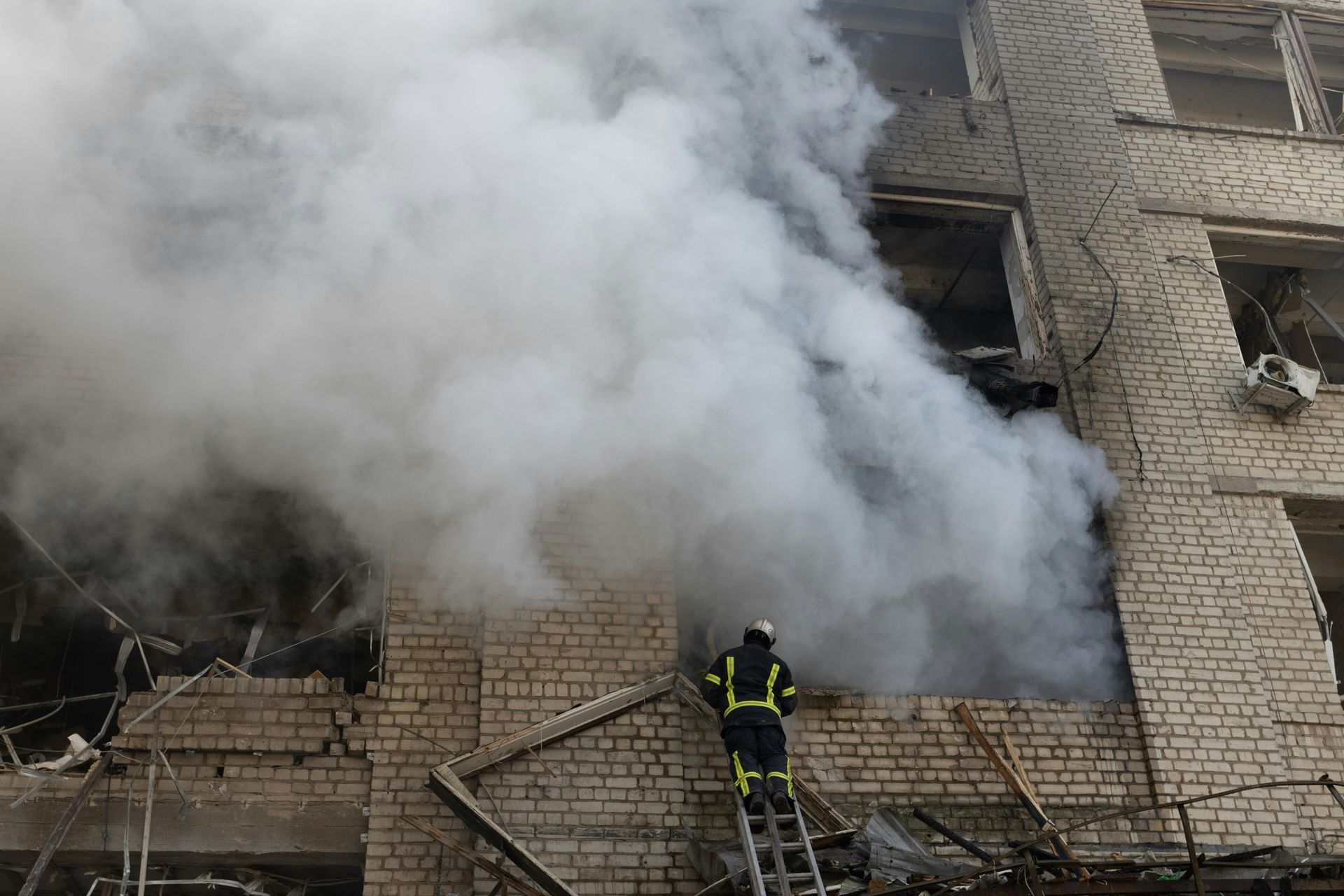 A fireman is climbing up a ladder to put out a fire in a building.