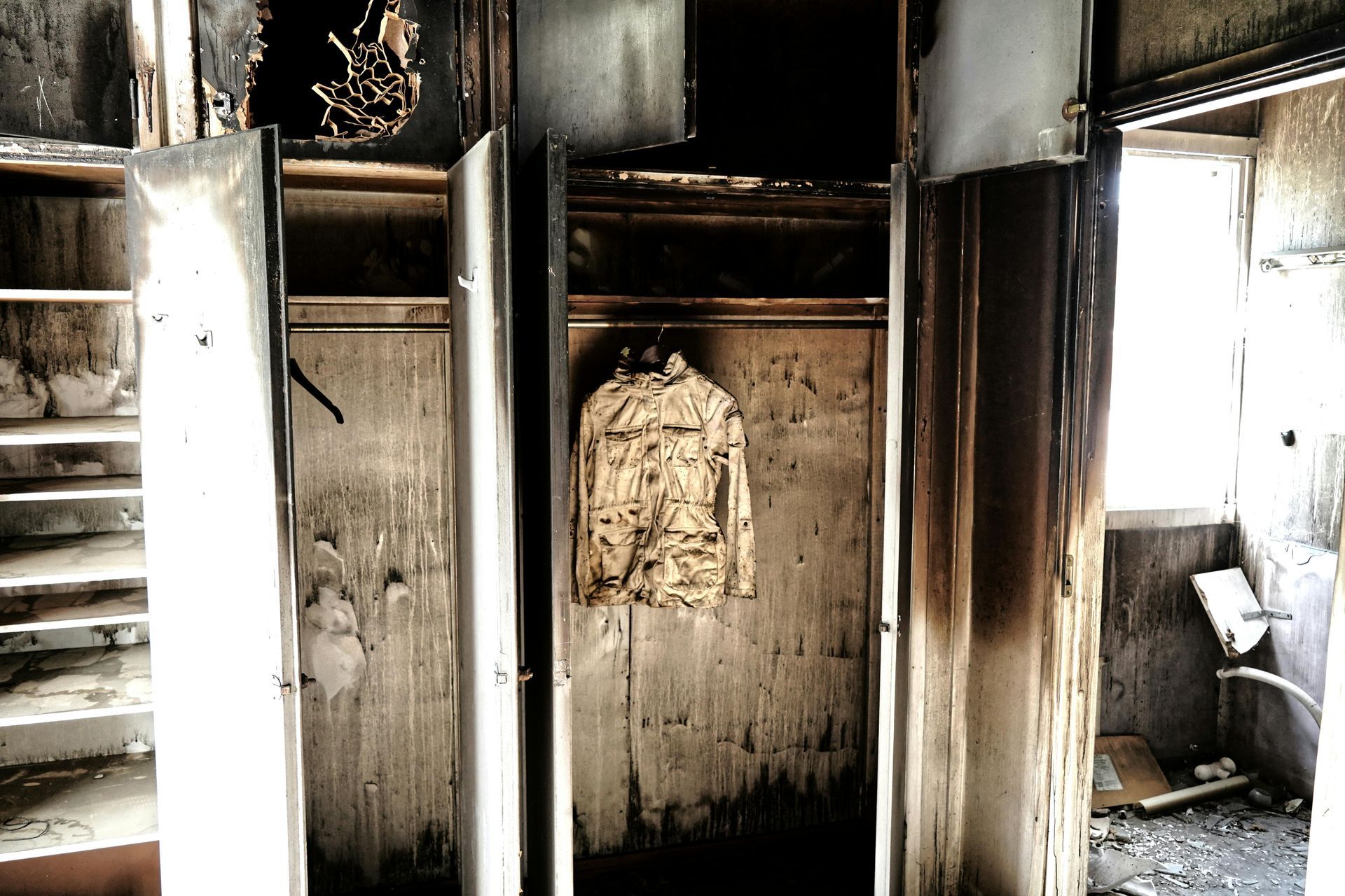 A dirty closet with a jacket hanging in it
