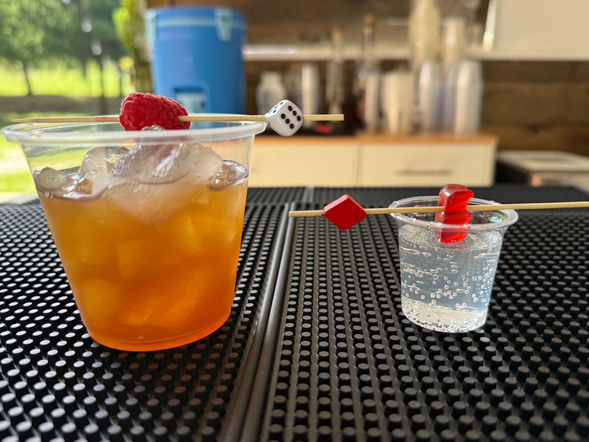 Red cocktail in a square-patterned glass, filled with ice and garnished with citrus, on a purple surface.