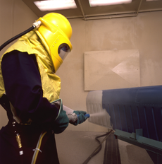 Un homme portant un casque jaune sable un objet bleu