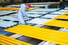 Un homme peint des tuyaux jaunes et blancs dans une usine.