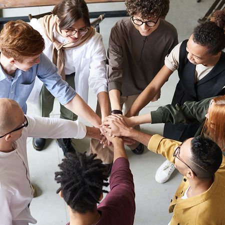 A group of people are putting their hands together in a circle.