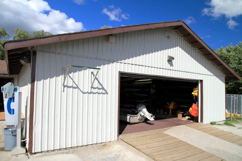 A White Garage With a Brown Roof and a Boat in It — DnA Steel Direct in Ciccone, NT