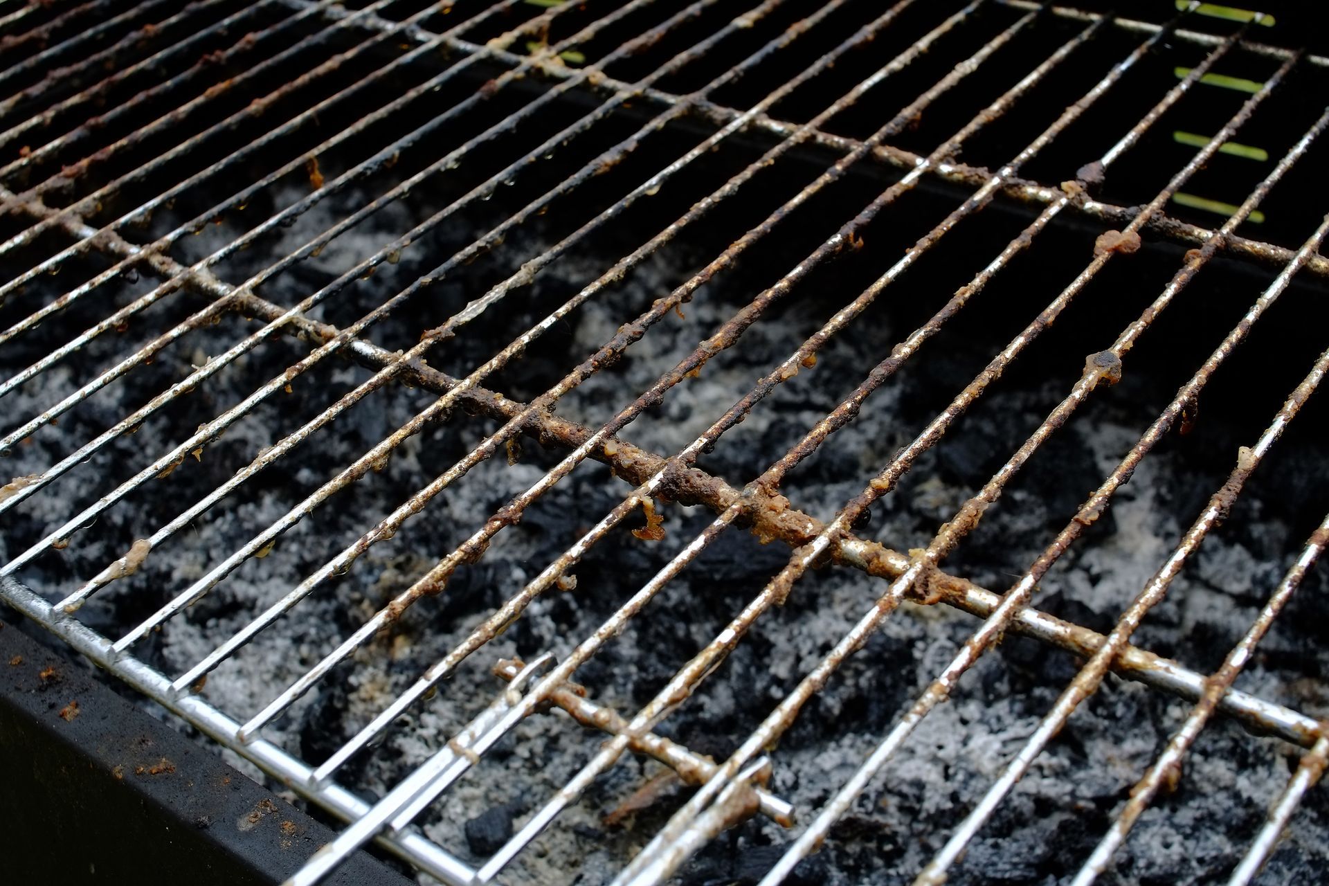 A close up of a dirty grill with a lot of ash on it.