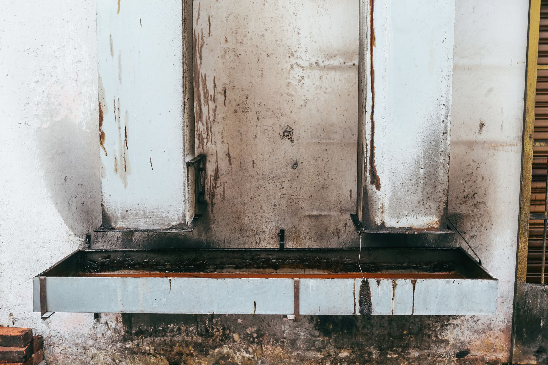 A close up of a dirty stove hood on a wall.